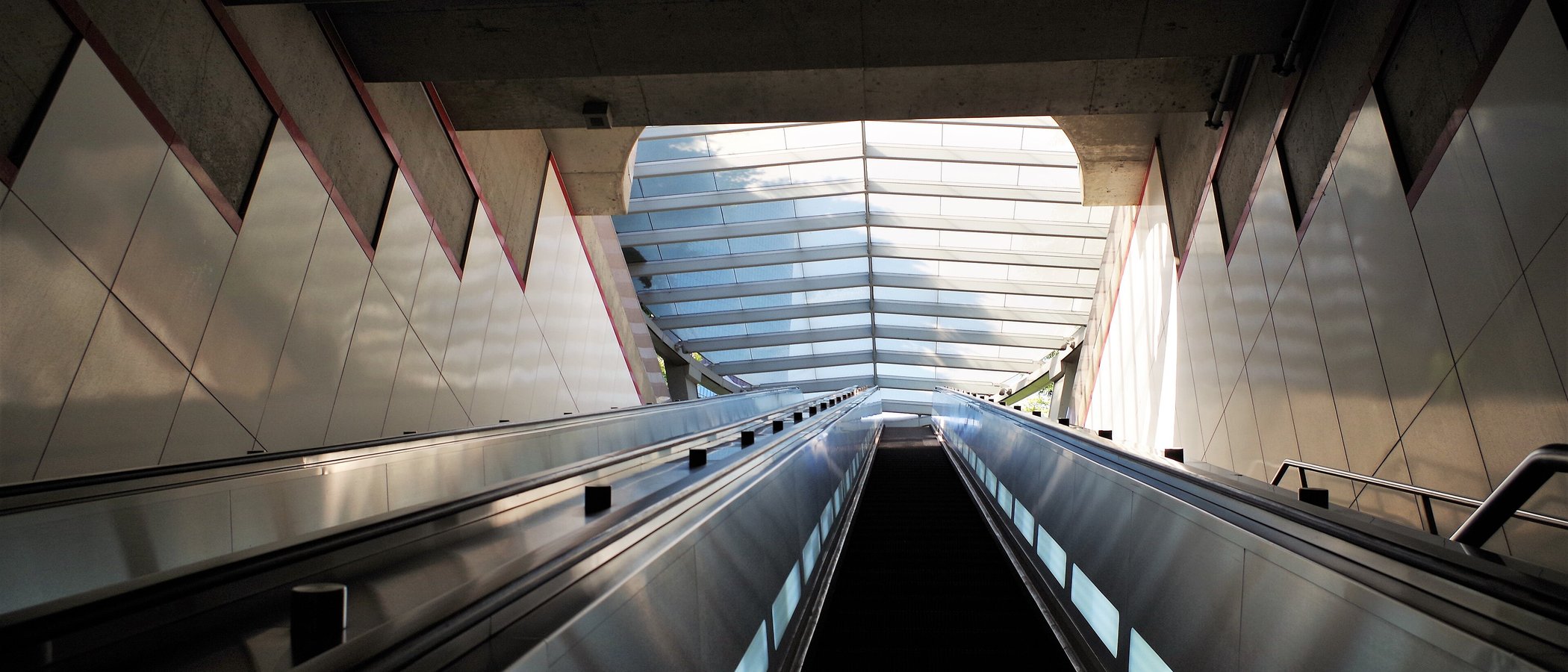 Looking up an empty escalator toward the glass canopy at Pershing Square station in downtown Los Angeles
