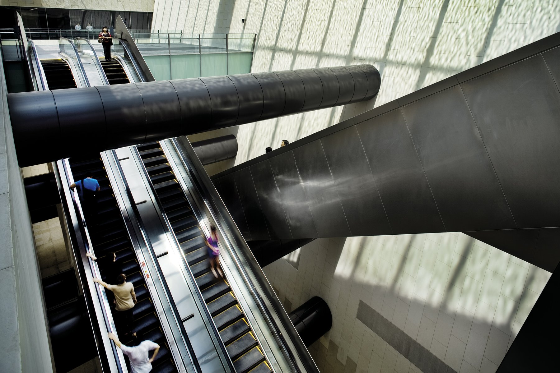Riders on the long escalators down into Bras Basah station on Singapore's MRT